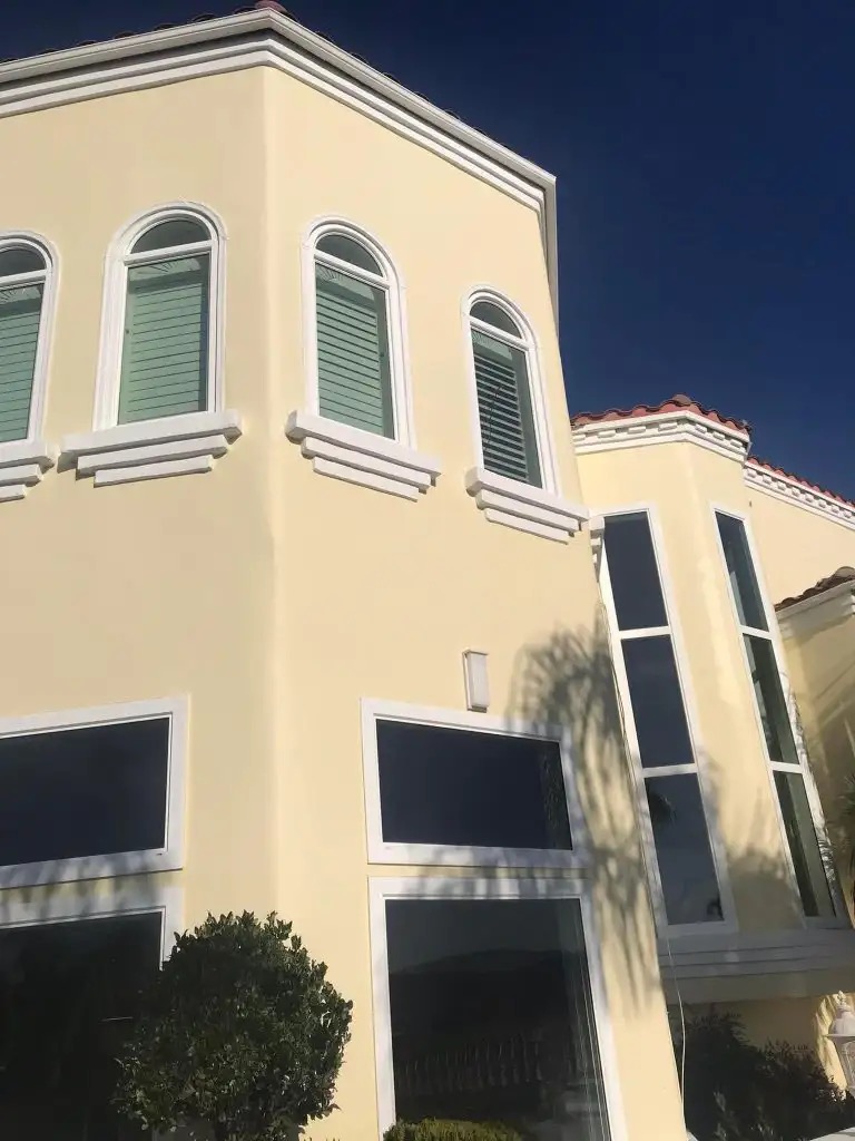 Home with white-framed arched and tall windows on a yellow stucco exterior